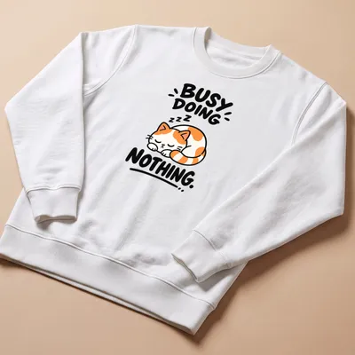 Kawaii line-art of a calico cat with text 'BUSY DOING NOTHING' in orange, white, black — printed on a unisex sweatshirt