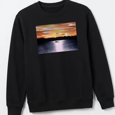 Boat silhouette against a colorful sunset in orange, yellow, and blue — printed on a unisex sweatshirt