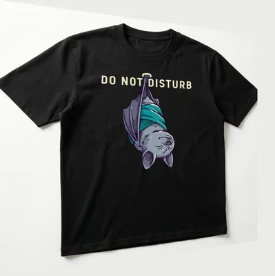 Cartoonish sleeping bat graphic with 'DO NOT DISTURB' text above in gray and teal — printed on a unisex t-shirt (angled view)