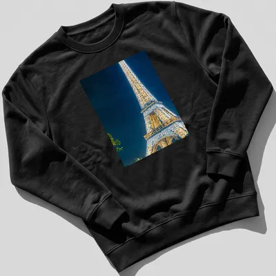 Photographic Eiffel Tower illuminated at night in gold, blue, and black — printed on a unisex sweatshirt