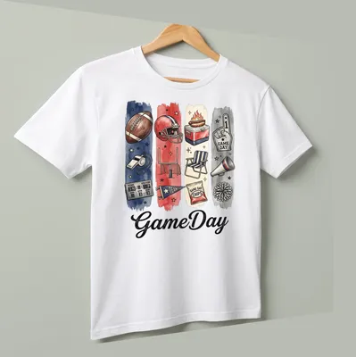 Watercolor print featuring GameDay and football elements in red, blue, cream, black, and brown — printed on a unisex t-shirt (angled view)