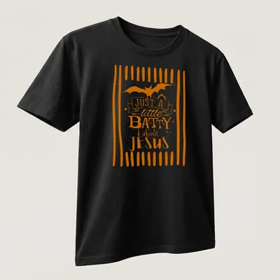 Playful T-shirt featuring a bat and the text 'Just A Little Batty About Jesus' in orange and white — printed on a unisex t-shirt (angled view)