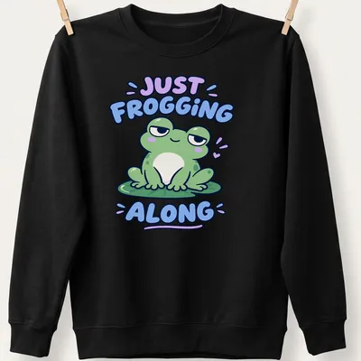 Kawaii design featuring a cute green frog with the phrase Just Frogging Along above it — printed on a unisex sweatshirt