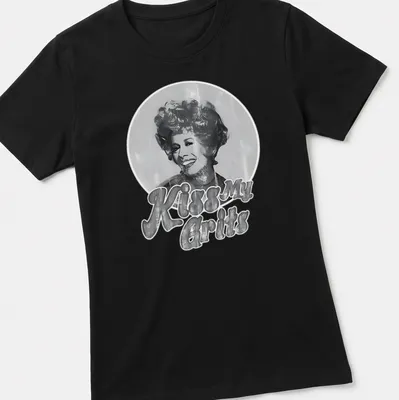 Smiling woman graphic with retro text 'Kiss My Grits' in black, white, and gray. — printed on a women's shirt