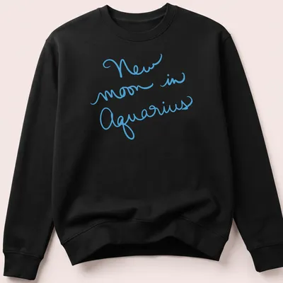 Handwritten script of New Moon in Aquarius on a light blue — printed on a unisex sweatshirt
