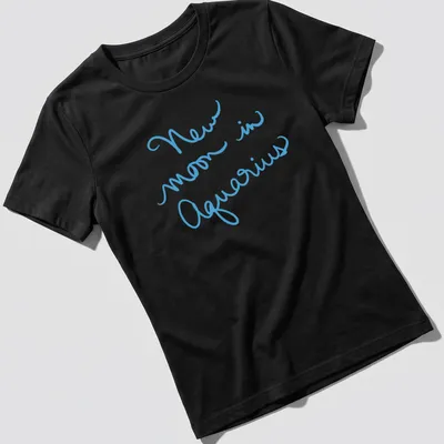 Handwritten script of New Moon in Aquarius on a light blue — printed on a women's shirt
