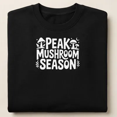 Bold typography Peak Mushroom Season t-shirt featuring mushrooms in green and brown — printed on a unisex sweatshirt