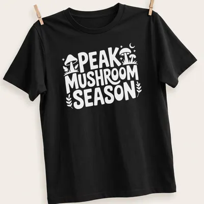 Bold typography Peak Mushroom Season t-shirt featuring mushrooms in green and brown