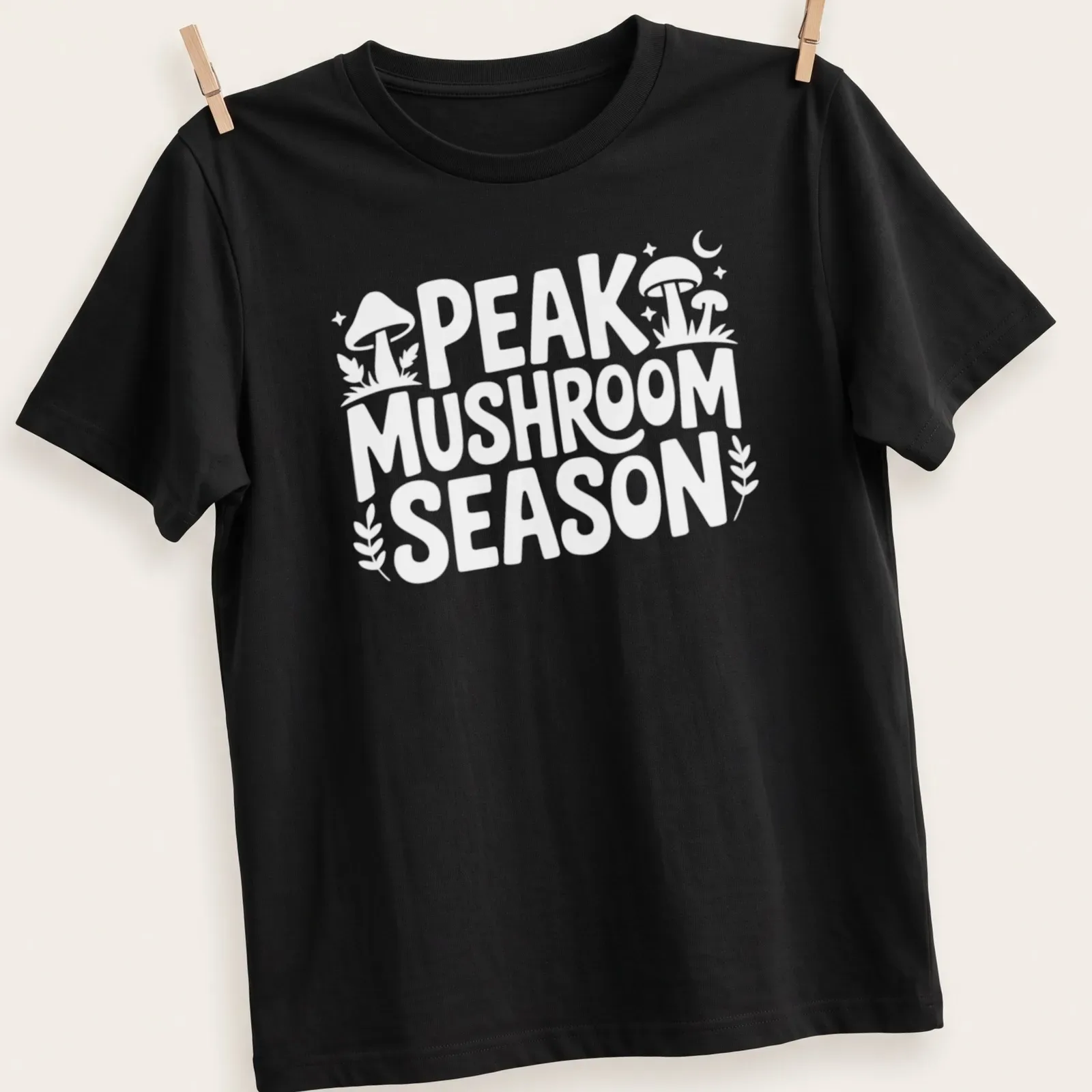 Bold typography Peak Mushroom Season t-shirt featuring mushrooms in green and brown — printed on a unisex t-shirt