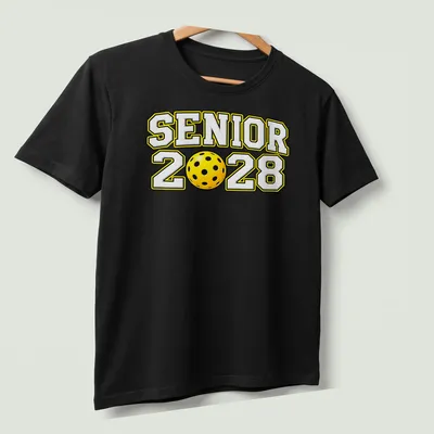 Bold text Senior 2028 with a pickleball graphic in yellow, black, and white — printed on a unisex t-shirt (angled view)