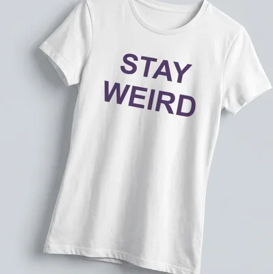 Purple t-shirt with the quote 'Stay Weird' in a playful font — printed on a women's shirt